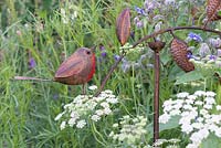 Metal bird sculpture amongst wild flowers