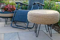 Rope covered tyre table on patio with reclining chair and decorative tyre planter in evening light