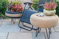 Rope covered tyre table on patio with reclining chair and decorative tyre planter in evening light