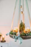 Hanging advent arrangement with gold candles, miniature christmas tree, Eucalyptus and Hebe foliage