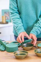 Woman adding oasis to holders to keep the foliage fresh