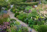 A bird's eye view of a contemporary garden design, a diagonal brick path separates beds of perennials and grasses, interspersed with Taxus - Yew -ball topiary