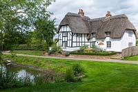 View from an ancient village duck pond to an old thatched cottage with a contemporary front garden 