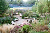 Looking down on wooden seating area amongst late summer planting. Sedlescombe Primary School, Sussex, UK. 