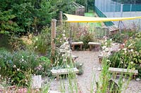 Wooden seating area for pupils and staff to enjoy amongst late summer planting. Sedlescombe Primary School, Sussex, UK. 