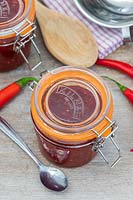 Chilli jam in kilner jar, chillies and tools for jam making.