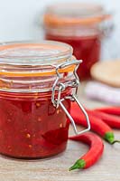 Chilli jam in kilner jar, chillies and tools for jam making. 
