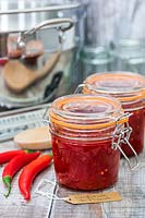 Chilli jam in kilner jar, chillies and tools for jam making with French label. 