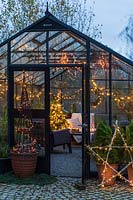 Greenhouse decorated for Christmas with tree, fairylights and candles - seen from the outside