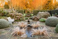 The Lower Rill Garden on a frosty December morning. Planting includes: Iris ensata, clipped yew balls and hedge 'Taxus baccata', Hydrangea macrophylla and beyond fastigate hornbeam, Carpinus 'Frans Fontaine' catches the dawn light.