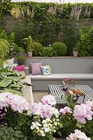  Cottage garden with built in benches and cushions, a metal table and raised beds