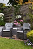 Grey rattan chairs in front of grey painted wall by lawn