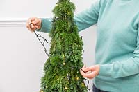 Woman decorating space saving christmas tree with LED fairy lights