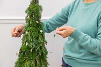 Woman decorating space saving Christmas tree with gold stars on a string