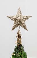A decorative star on top of a space saving Christmas tree decorated with stars and lights