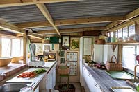 Old fashioned vintage kitchen area for vegetable preparation in garden room, filled with gardening paraphanalia