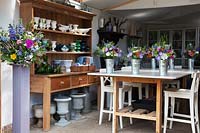 The flower arranging studio with wedding arrangements ready, collections of vases, urns and buckets.