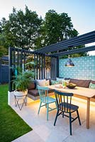 View of illuminated dining area with colourful chairs, modern pergola and industrial style lamp.