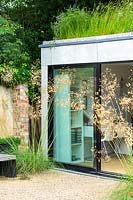 The entrance to a modern extension with green roof, flanked by Stipa gigantea.