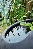Melica ciliata beside a contemporary sculptural pond.