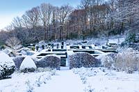 View from the Grasses Parterre to the snow covered Hedge Gardens and wood in background. Hedges and columns of taxus baccata and wave-form hedge of Fagus sylvatica in foreground. Veddw House Garden, Monmouthshire