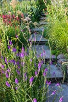 Densely-planted beds of perennials and annuals, either side of stone steps 