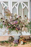 Autumnal floral arrangement in urn with dried and foraged florals inc echinacea, Clematis, bracken, hydrangeas, echinops.