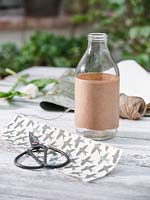 Milk bottle wrapped with brown paper. 
