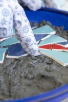 Close up of woman placing mirror shards among the pieces of smashed plate