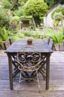 Decked dining area with table and chairs in a cottage garden in June