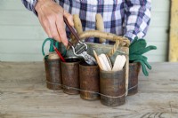 Woman placing secateurs into tin can caddy containing other items
