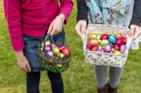 Children holding baskets with colourful chocolate eggs at Easter