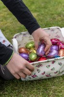 Child collection colourful chocolate eggs in basket
