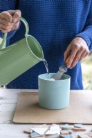 Woman pouring water into a pot of powder grout