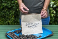 Placing seed bombs into brown paper bag