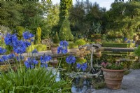 View of a formal pool with sculptural fountain in a country garden in summer - July