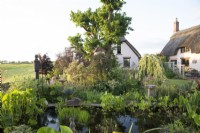 View of a garden pond with thatched cottages beyond