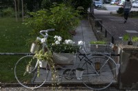 Garden feature - old bicycle frame adorned with ivy and geranium and flower pots made from tin cans.  Karlsruhe - Germany