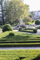 View over the formal parterre of lines of clipped Box hedges and mounds separated by grit paths. Fountain in centre.  Lisbon, Portugal, September.