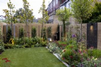 Contemporary suburban garden in London with colourful borders and lighting