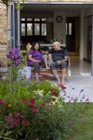 Couple and son sitting on patio in contemporary garden 