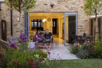 Couple sitting on patio in front of doors in a suburban garden
