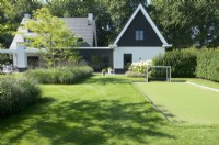 Playground with goal and borders with grasses, Verbena and trees in the middle of the lawn.