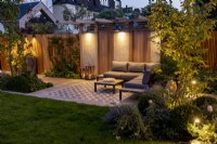 Modern garden with patio and pergola at night with lighting
