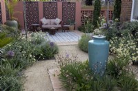 Contemporary gravel garden in suburban garden with tall ceramic container water feature and Moroccan style patio