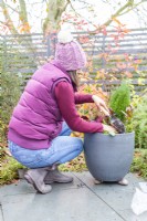 Woman filling in any gaps in the container with compost