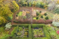 View over mature clipped hedges of Yew containing three distinct garden rooms. Wave form hedge of Beech. Area planted with ornamental grasses in blocks with several clipped Yews in cone form; image taken with drone. November. Autumn.