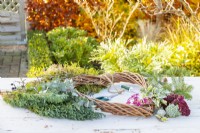 Wreath, snips, wire, plants and moss laid out on a wooden surface