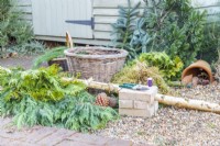 Bricks, secateurs, wire, moss, conifer branches, basket and a large birch stick laid out on the ground