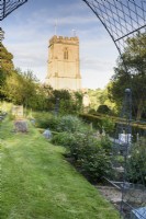 Formal vegetable garden on sloping ground at the Old Rectory, Netherbury, Dorset in May with a backdrop of St Mary's Church